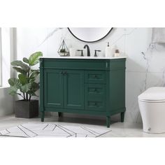 a white toilet sitting next to a green cabinet in a bathroom on top of a rug