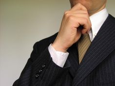 a man in a suit and tie is posing for the camera with his hand on his chin