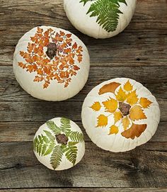 three painted pumpkins sitting on top of a wooden table next to an iphone screen