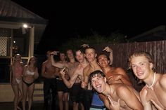 a group of men and women posing for a photo in their bathing suits at night