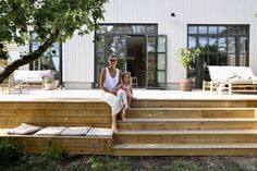 a woman and child are sitting on the steps in front of a house that has been built