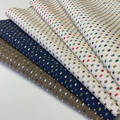 four different colored polka dot fabric on a white tablecloth, with one folded in half