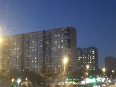 the sun shines brightly in front of an apartment building on a city street at night