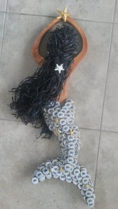 an image of a mermaid doll made out of buttons and yarns on the floor