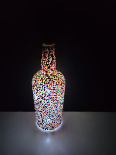 a colorful glass vase sitting on top of a white table next to a black wall