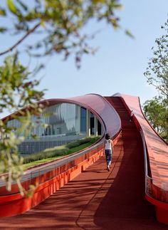 a woman walking down a red walkway next to trees