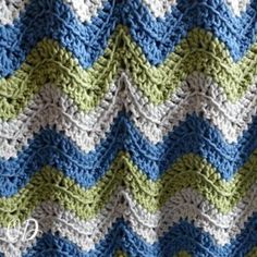 a crocheted blanket with blue, green and white stripes