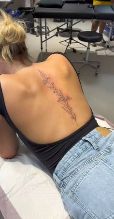 a woman laying on top of a bed with a tattoo on her back