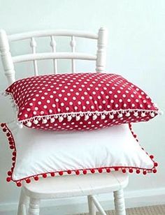 three pillows stacked on top of each other in front of a white chair with red and white polka dot cushions