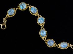 "Moonstone Gold Bracelet delicately-designed and enhanced with 7 opulent Rainbow Moonstones, giving a sensual, romantic aura to this Elizabethan-inspired piece. Available in size 7 and 8. * Handcrafted in 18K Gold, thickly coated over .925 Sterling Silver. * Handmade Cable Chain adjusts 6.5\"-7.5\" (Size 7) or 7.5\"-8.5\" (Size 8). (Size 8 coming soon!) * From the Tibetan Moon Gold Collection, featuring high-quality Rainbow Moonstones from India, to enhance your intuition, provide protection &am Luxury Moonstone Jewelry For Formal Occasions, Formal Yellow Gold Moonstone Jewelry, Celestial Gemstone Jewelry For Formal Occasions, Luxury Yellow Gold Moonstone Jewelry, Elegant Hallmarked Moonstone Jewelry, Formal Gold Bracelets With Natural Stones, Luxury Gold Moonstone Jewelry, Formal Gold Bracelets With Gemstone Accents, Luxury Oval Bracelets With Natural Stones