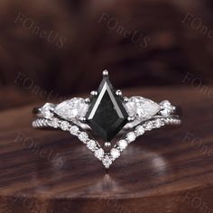 a black and white diamond engagement ring on top of a wooden table with diamonds around it