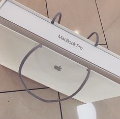 an apple macbook pro box sitting on the floor with its lid open and string wrapped around it