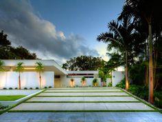 a modern house with palm trees in the front yard