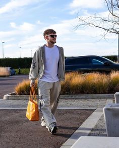 a man walking down the street carrying a yellow bag