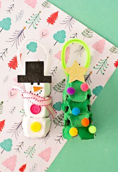 an ornament is sitting next to a christmas tree with a snowman on it