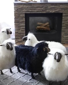 four sheep are standing in front of a fireplace