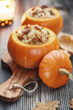 three pumpkins sitting on top of a wooden cutting board