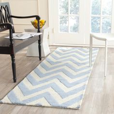 a white and blue area rug on the floor in front of a wooden table with two chairs