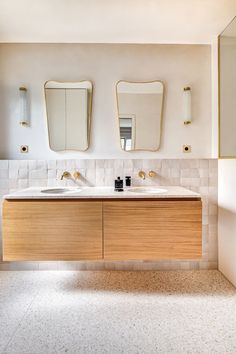 a bathroom with two sinks and mirrors on the wall