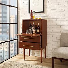 a wooden cabinet with liquor bottles and glasses on it in front of a brick wall