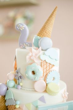 a three tiered cake with ice cream and doughnuts on top, decorated in pastel colors