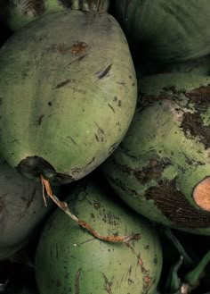 a pile of green coconuts sitting on top of each other with peeling paint all over them