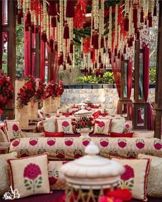 a room filled with lots of couches covered in red and white pillows next to flowers