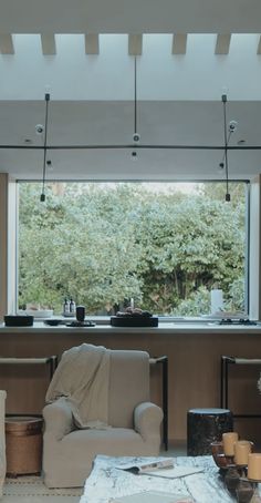 a living room filled with furniture and a large window overlooking the trees in the distance