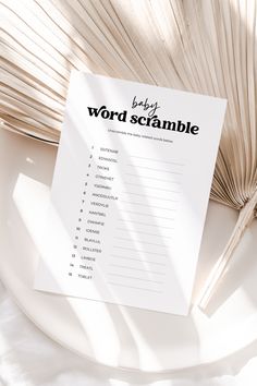 a baby word scramble sitting on top of a white plate next to a palm leaf