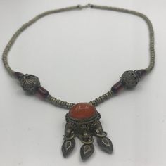 This is part of Chairish’s Costume Jewelry assortment.  Bold Carnelian Cabochon pendent is at the center of this Tibetan necklace. Also known as buddhist jewelry in the region of the former Tibet, or near Bhutan/Nepal. The piece is a chain of brass rings and there is some detailing of ruby red glass trumpet beads.   Pieces with Carnelian are said to bring joy, motivation, endurance, leadership, and courage into our lives. In the past, warriors would wear carnelian into battle to boost courage an Traditional Orange Jewelry For Healing, Traditional Orange Healing Jewelry, Traditional Silver Carnelian Necklace, Vintage Gemstone Beads Jewelry For Meditation, Traditional Orange Gemstone Jewelry, Antique Amber Necklace With Gemstone, Antique Amber Gemstone Necklace, Traditional Agate Pendant Necklace, Traditional Carnelian Gemstone Jewelry