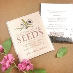 a seed packet and some pink flowers on a brown surface with a note about wildflower seeds