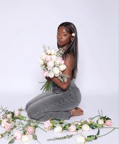 a woman sitting on the ground with flowers around her