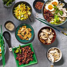 a table topped with plates and bowls filled with food next to utensils on top of a white table cloth