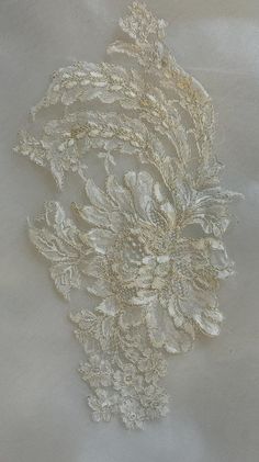 an embroidered fabric with white flowers and leaves on the back of it's surface