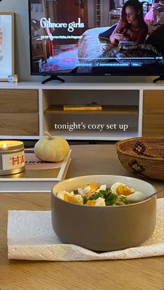 a bowl of food sitting on top of a table in front of a flat screen tv