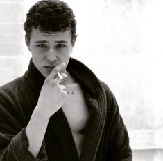 a young man is brushing his teeth with a towel around his neck and looking at the camera