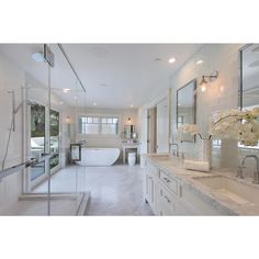 a large white bathroom with two sinks and a bathtub in the middle of it