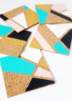 four cork coasters with different colors and shapes on top of each other, sitting on a white surface