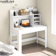 a white desk with a laptop on top of it next to a window and bookshelf