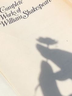 the shadow of a person holding a skateboard in front of an open copy of shakespeare's complete works of william shakespeare