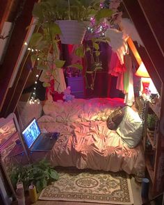 a room with a bed, laptop and plants in it