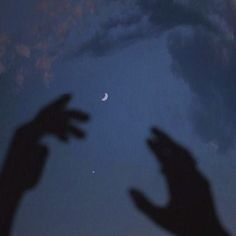 two hands reaching up to the sky with a crescent moon in the distance behind them