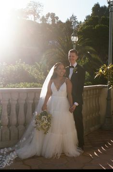 a bride and groom pose for a photo on their wedding day in front of the sun