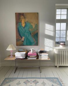 a living room with a painting on the wall next to a table filled with books