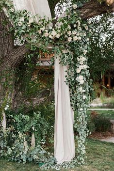 an outdoor wedding ceremony with white flowers and greenery