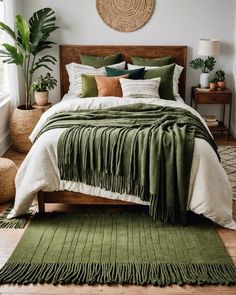 a bed with green blankets and pillows on top of it in a bedroom next to potted plants