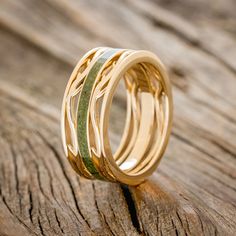 two wedding rings with gold and white wood inlays on a piece of wood