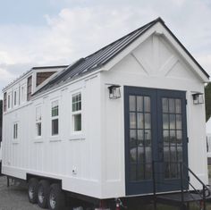 a tiny white house on wheels parked in a lot