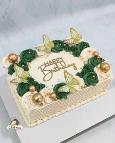 a birthday cake with white frosting and green decorations