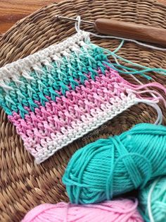 three balls of yarn sitting on top of a woven basket next to a knitting needle